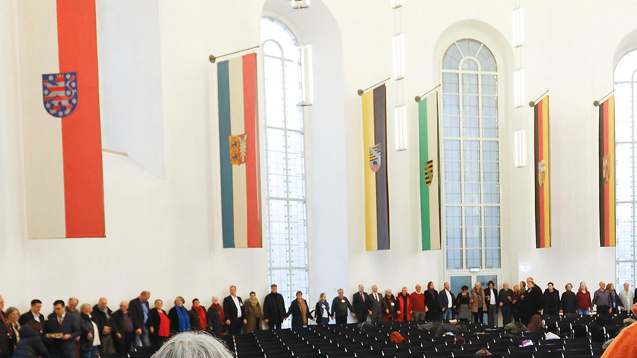 Abendmahlsteilnehmende Menschenkette entlang der Wand