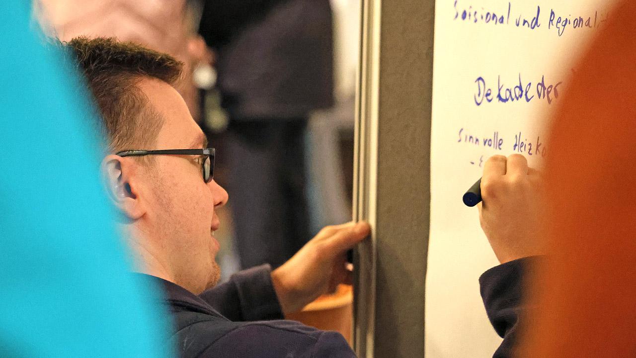 Workshop während der Synode Ein Mann schreibt Wörter auf ein Flipchart-Papier