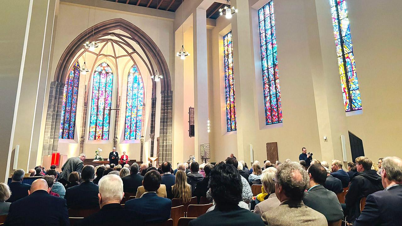 Eröffnungsgottesdienst Viele Menschen im Kirchenraum, im Hintergrund bunte Kirchenfenster