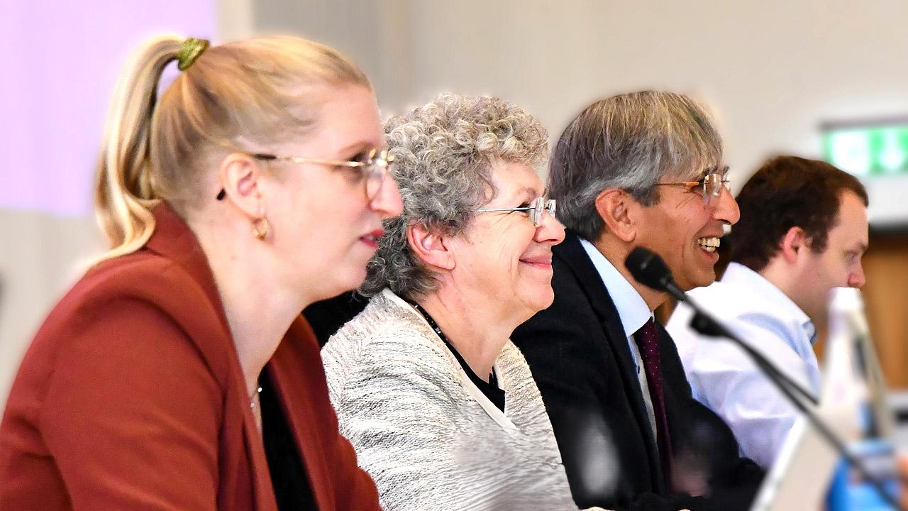 Kirchensynodalvorstand Drei Menschen nebeneinander sitzend, dahinter weitere