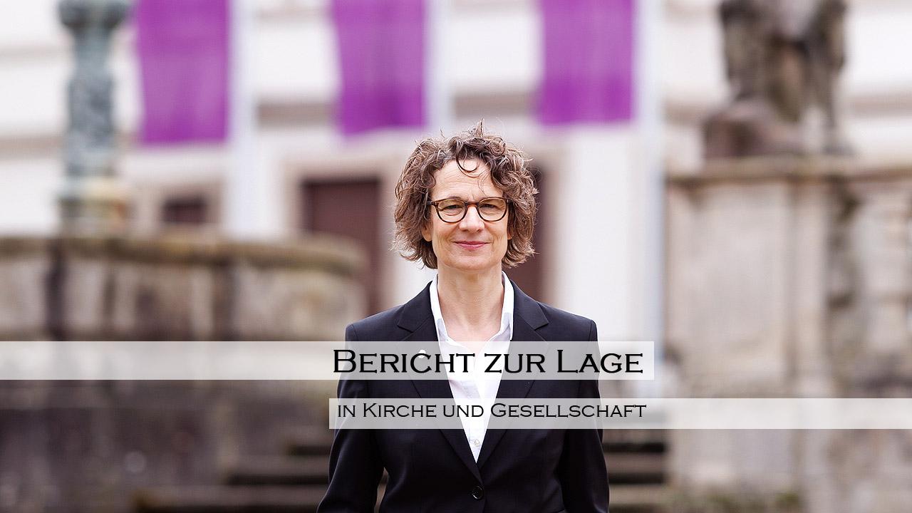 Kirchenpräsidentin vor der Kirchenverwaltung, davor die Schrift: Bericht zur Lage in Kirche und Gesellschaft