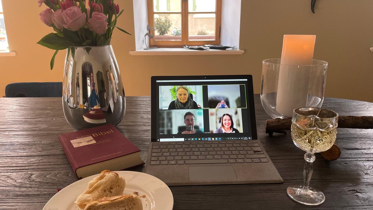 Altar mit Kerzen, Brot und Wein oder Saft, in der Mitte ein aufgeklappter Laptop