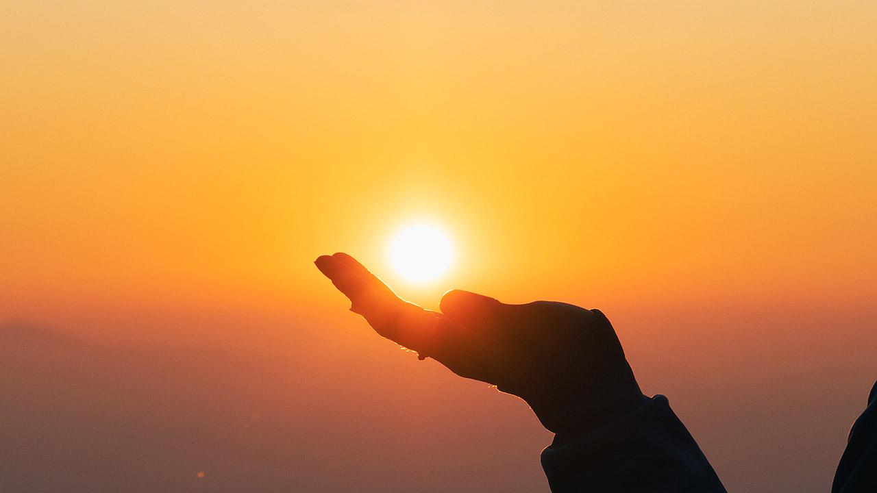 Untergehende Sonne leuchtet über einer Hand