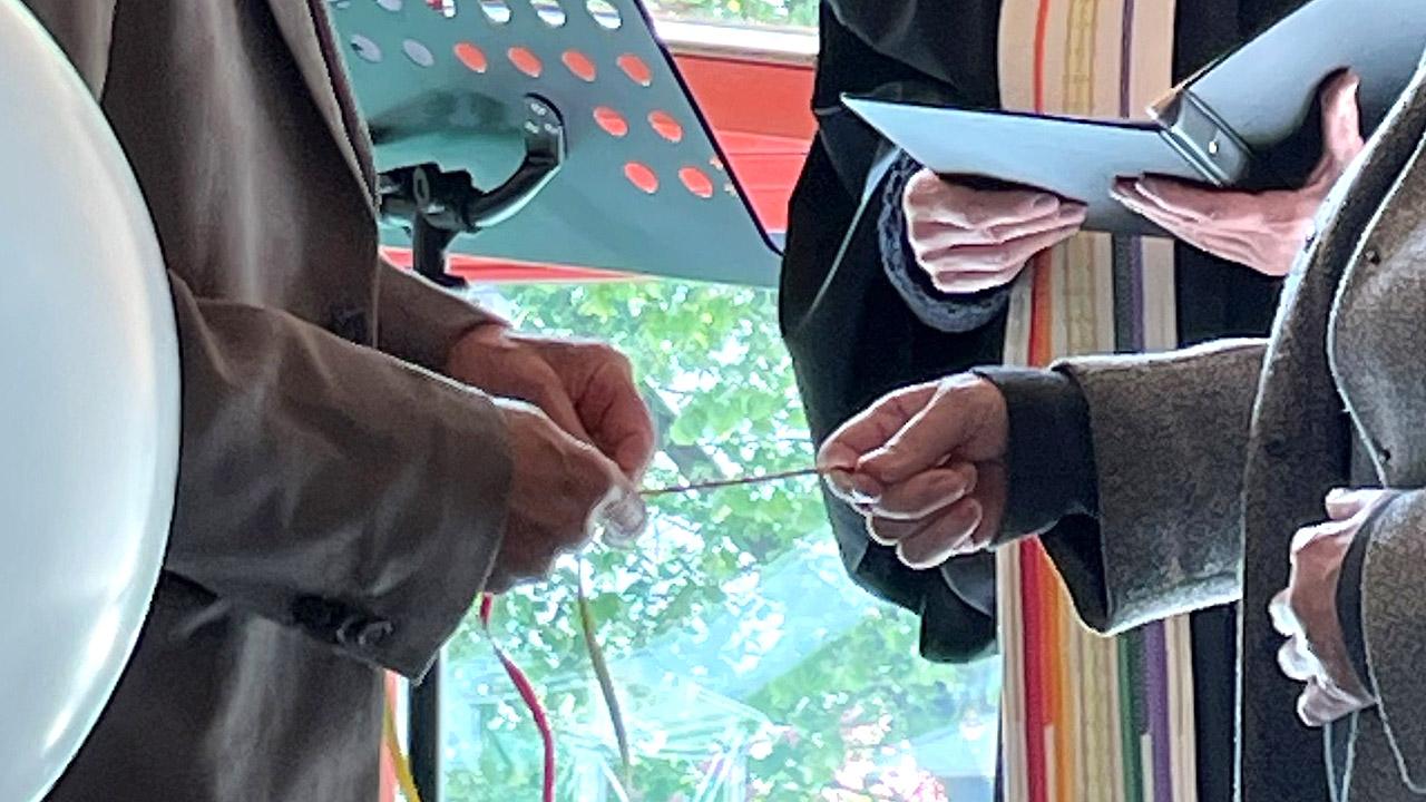 Trauung to go - Segensband Die Hände des Mannes flechten ein Segensband, die Hände der Frau halten es fest