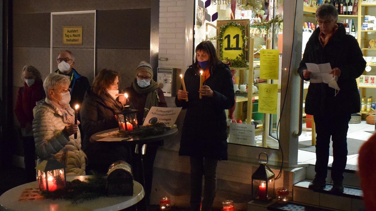Ein paar Menschen vor einem kleinen Laden musizieren und es brennen Kerzen