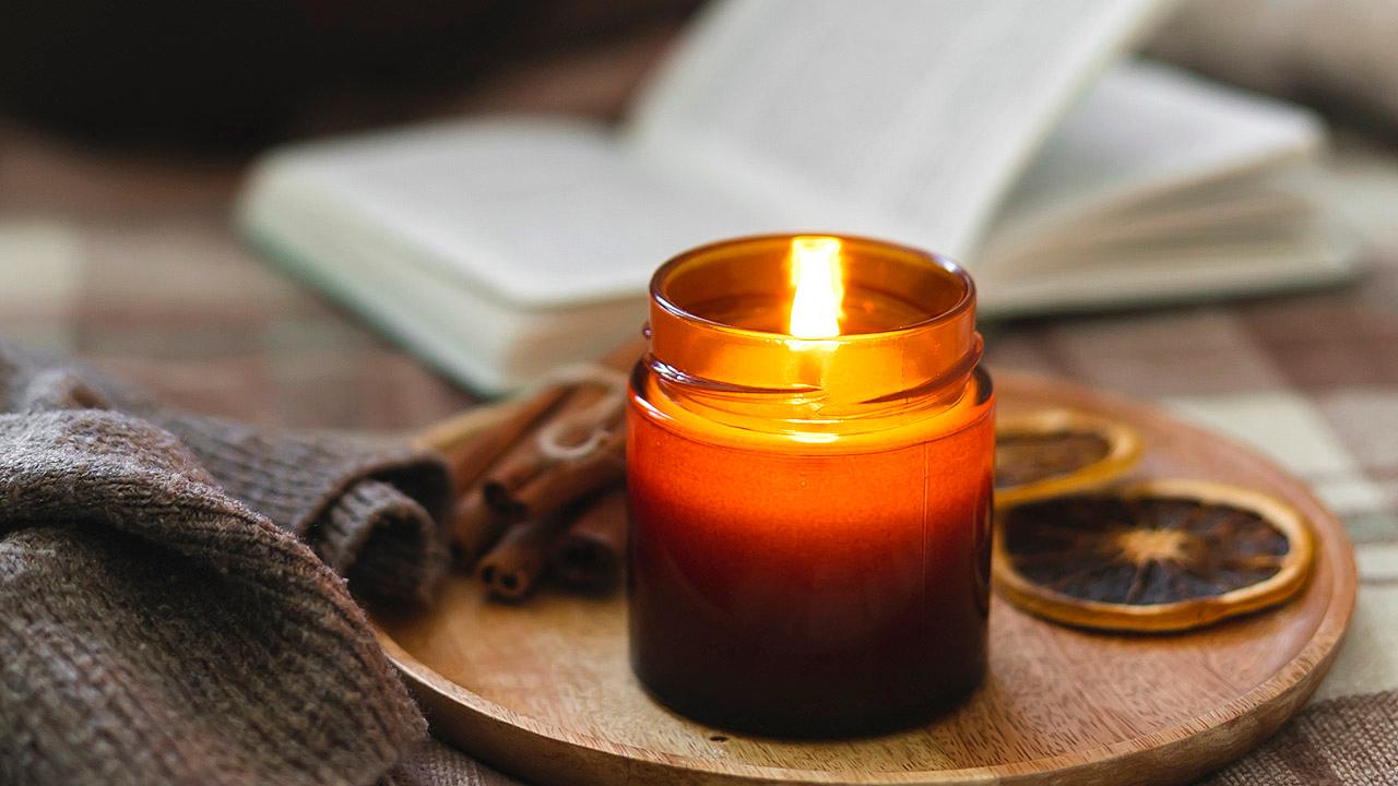 Kerze auf einem Tablett, im Hintergrund ein Buch