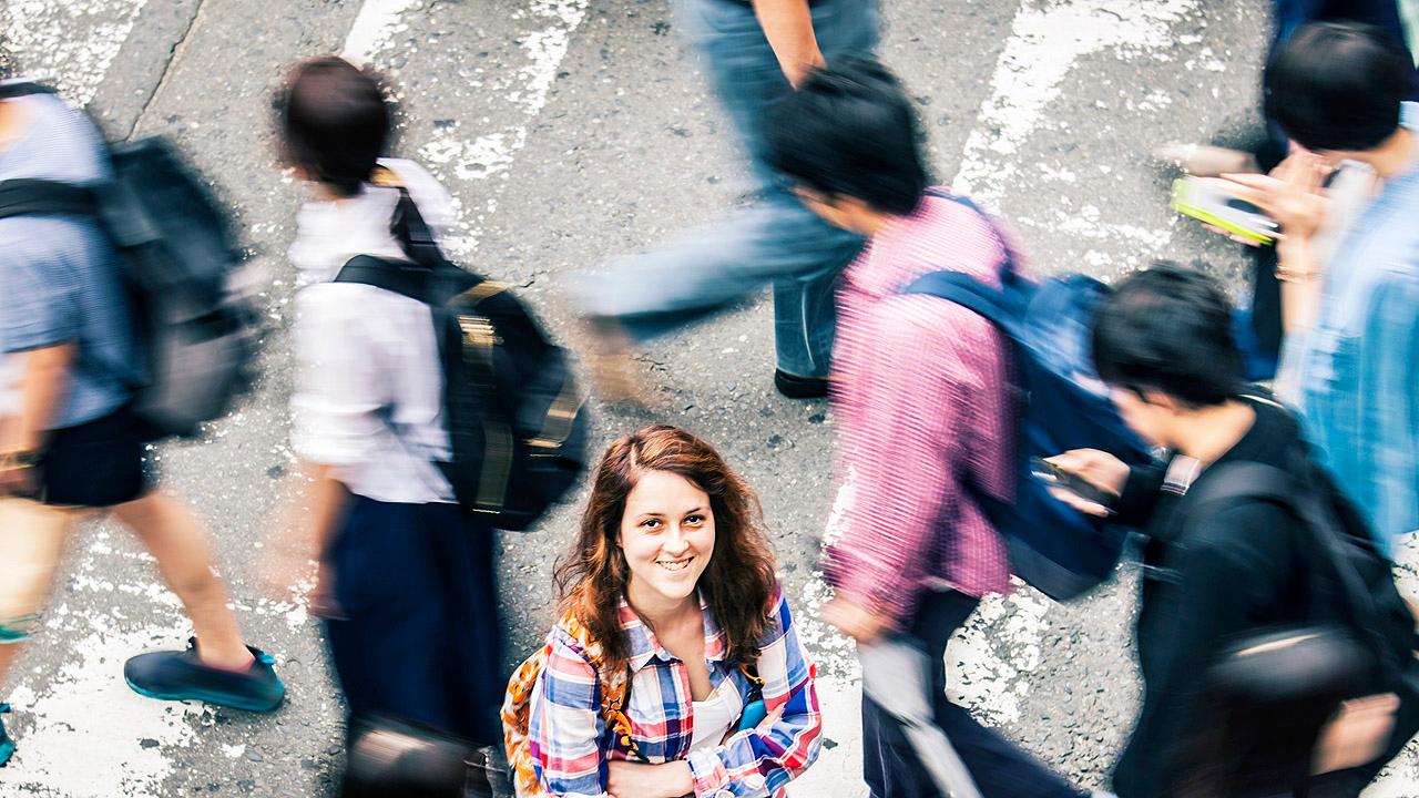 Eine Frau bleibt inmitten einer hektischen Menschenmenge stehen