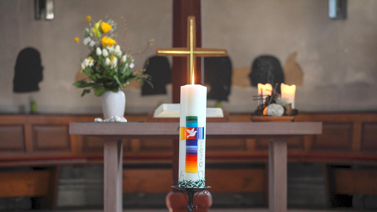 Osterkerze Große Osterkerze in Farben gelb, orange, rot, blau und lila gestaltet im Altarraum einer Kirche