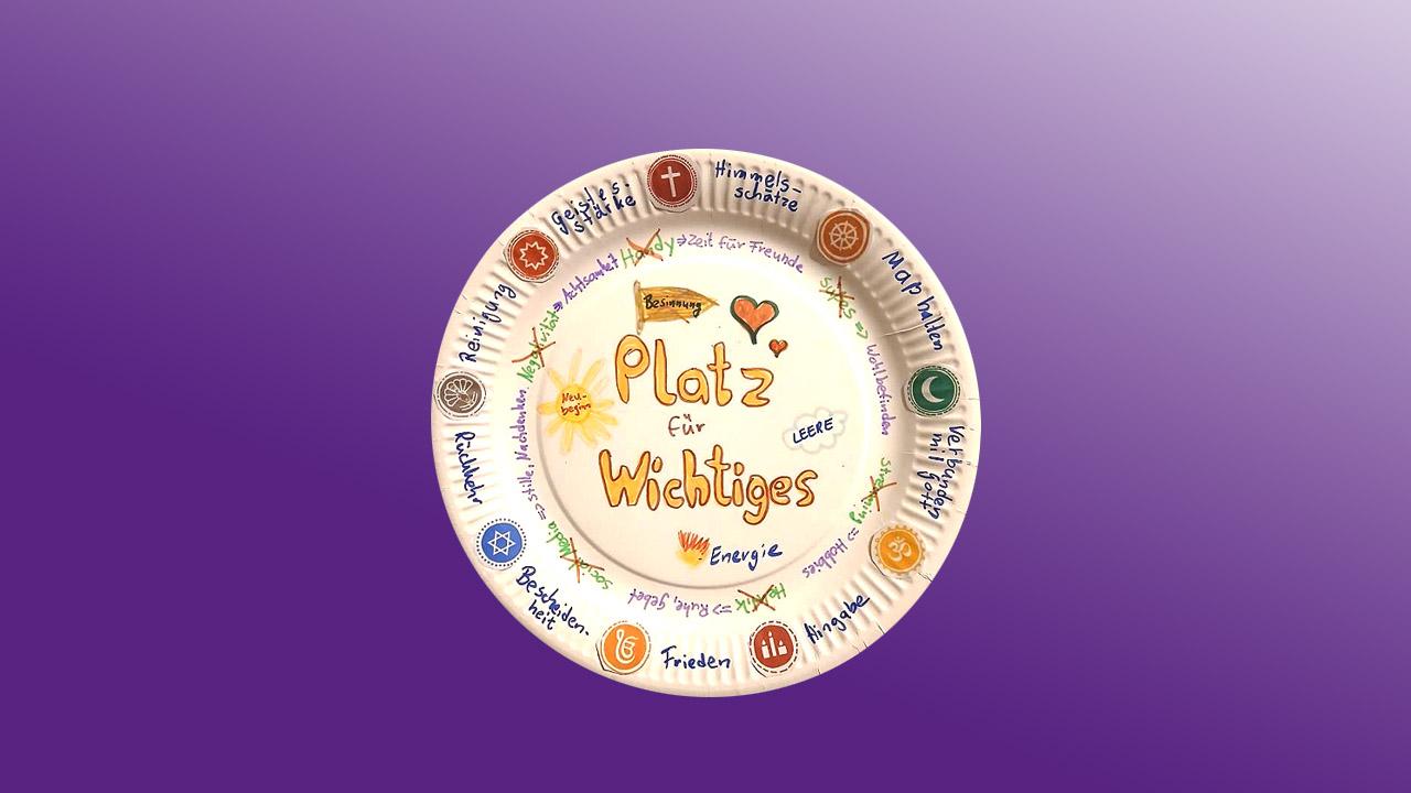 Kreativ gestalteter Pappteller mit Symbolen der Religionen und den Worten "Platz für Wichtiges"