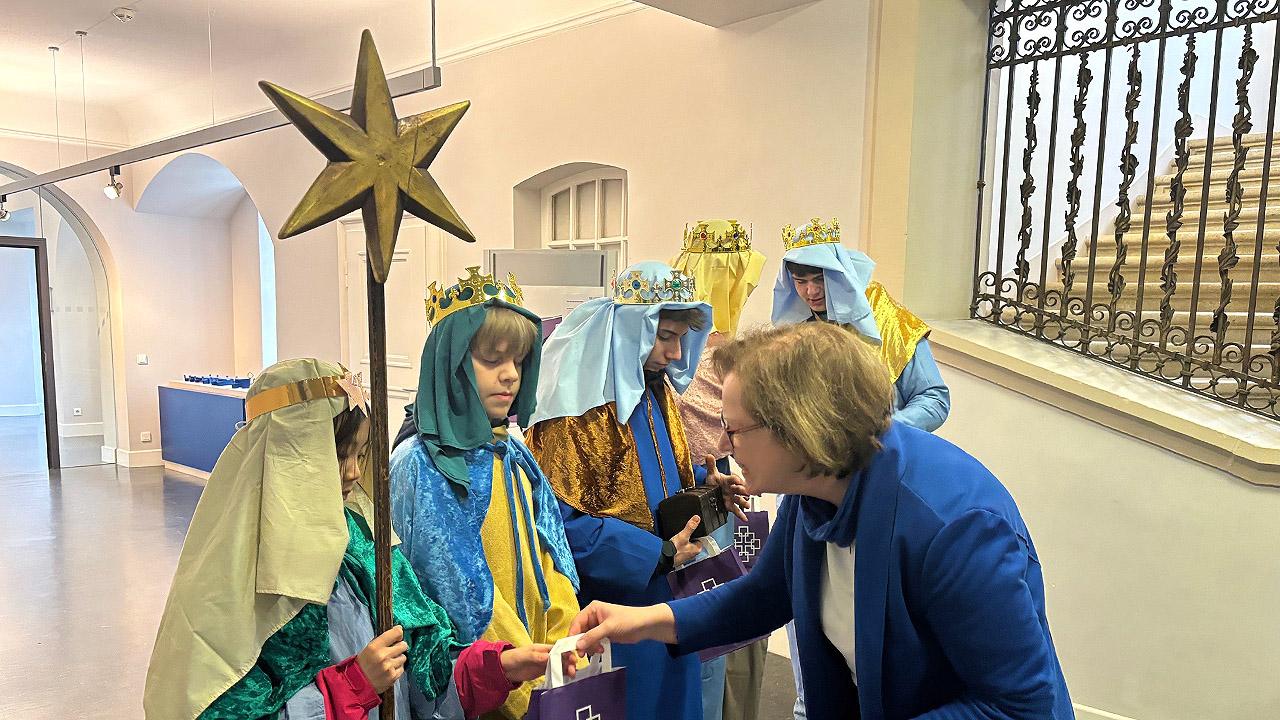 S ternsinger in der Kirchenverwaltung Ulrike Scherf überreicht kleine Tüten mit EKHN-Logo an die Kinder
