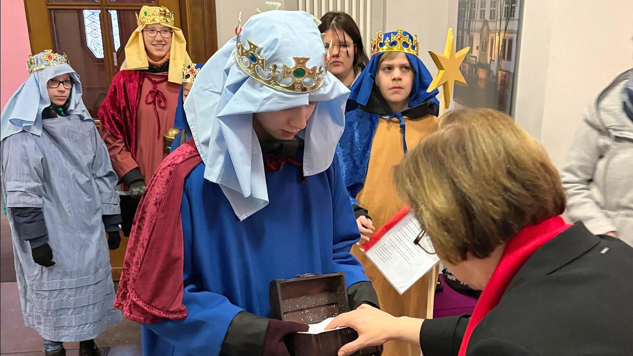 Sternsinger Ulrike Scherf spendet in ein Kästchen der Sternsinger