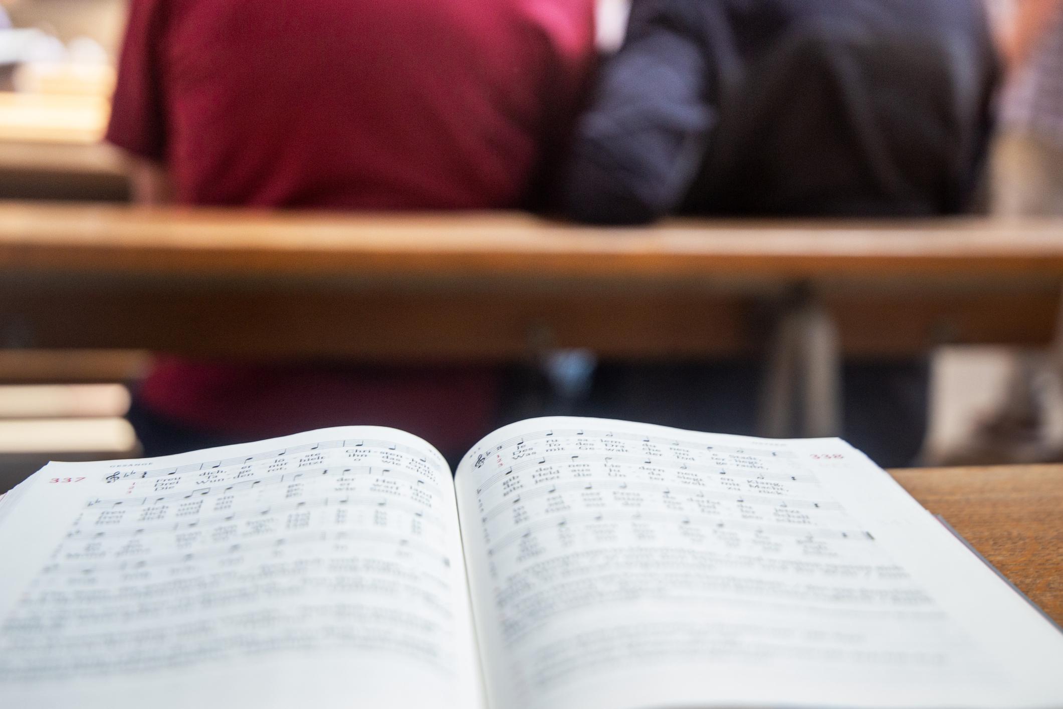 Gesangbuch Ein aufgeschlagenes Gesangbuch liegt auf einer Kirchenbank.