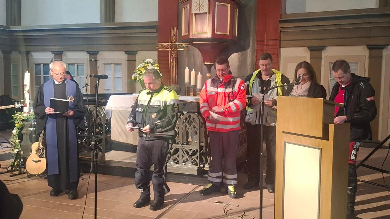 Motorrad-Gottesdienst Mehrere Menschen und ein Geistlicher halten Fürbitten im Altarraum einer Kirche