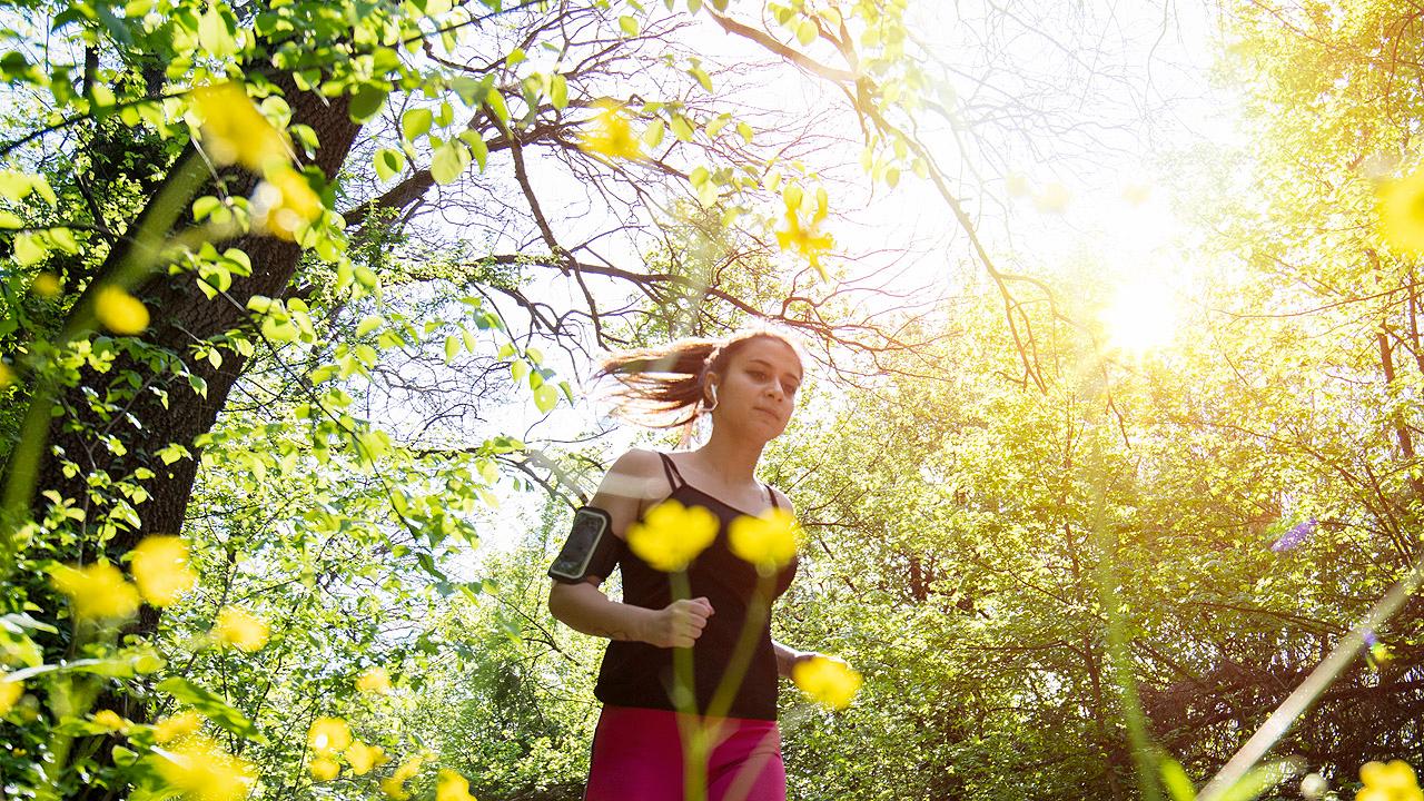 Eine Frau joggt durch die blühende Natur