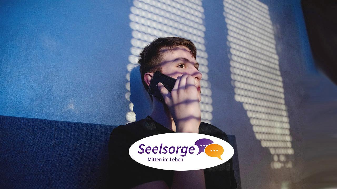 Ein junger Mann telefoniert im Dunklen