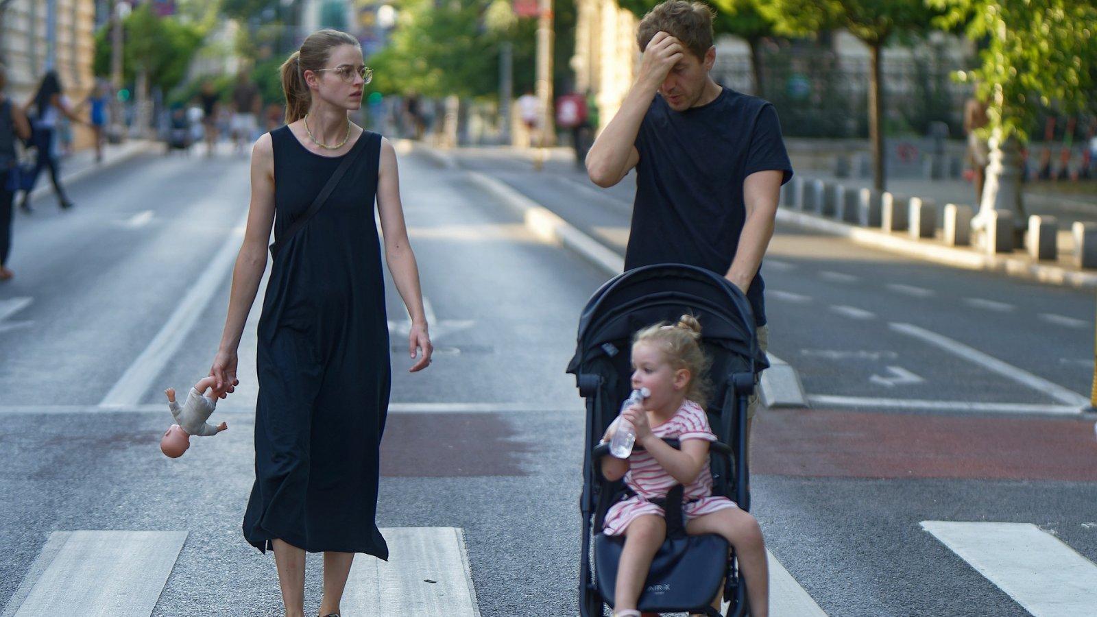 Famile Dreiköpfige Familie überquert eine Straße, Kind im Kinderwagen