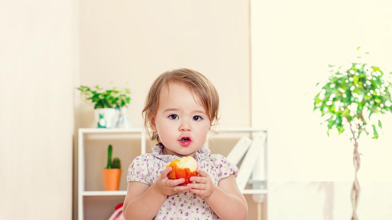 Ein kleines Mädchen isst einen Apfel