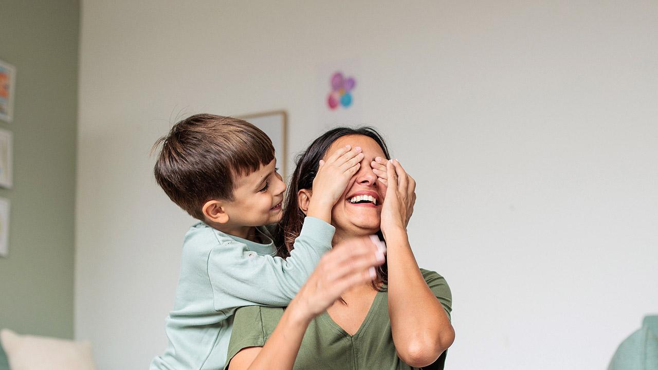 Junge hält Mutter die Augen zu