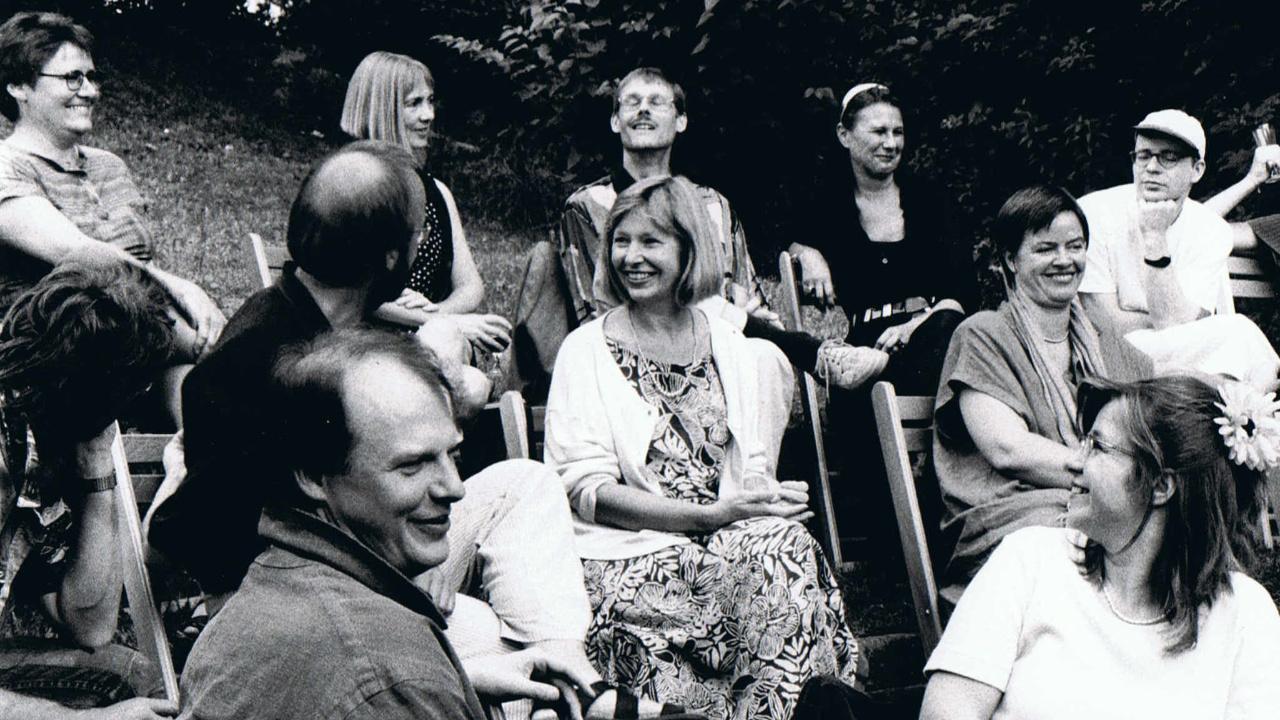 Bibliodrama Workshop Burckhardthaus Ute Knie sitzt inmitten vieler Menschen im Garten, es wird gelacht, musiziert, sich unterhalten