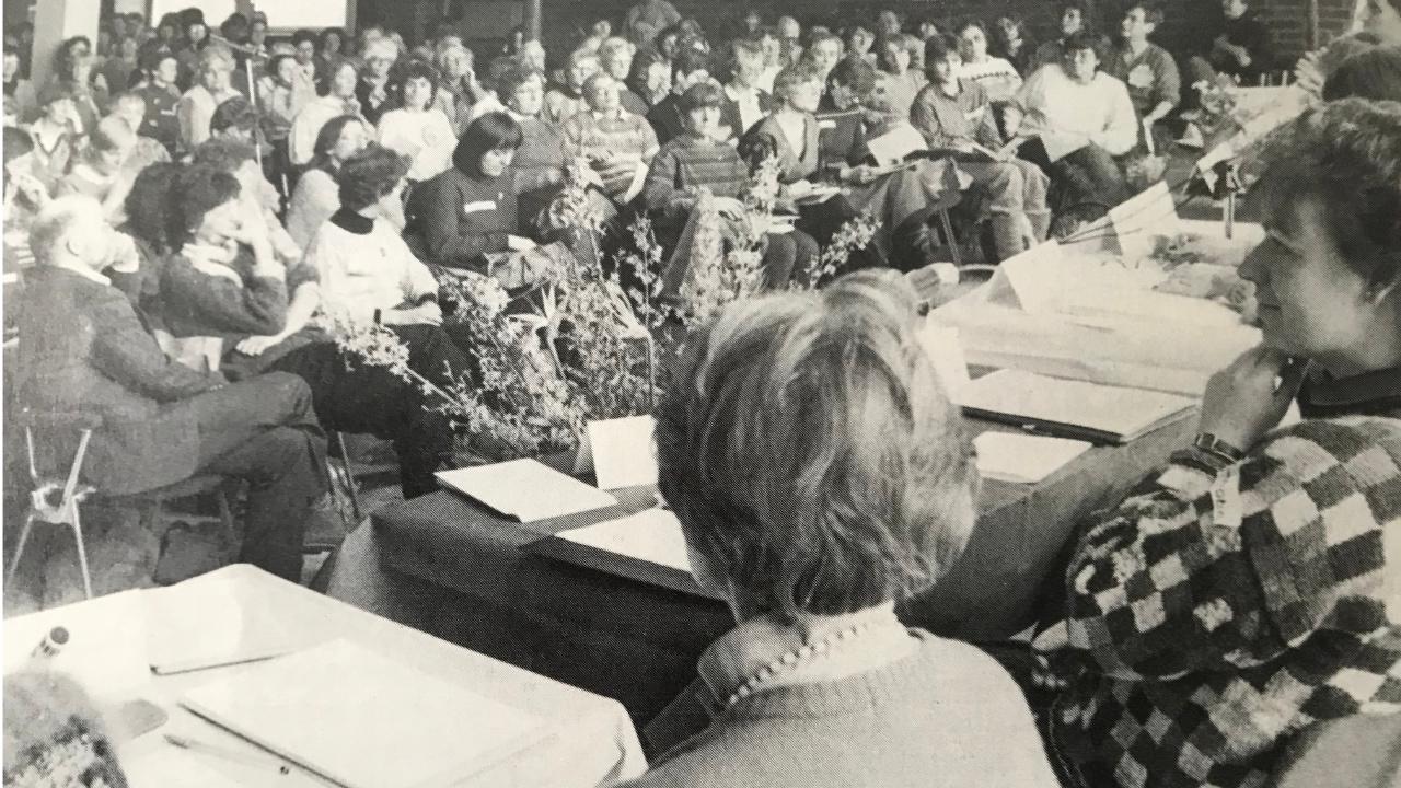 Frauenanhörung EKHN 1986 Über 400 Frauen sitzen in einem Saal in Darmstadt, mehrere Frauen sitzen auf dem Boden mit dem Rücken zur Kamera. Das Bild ist schwarz-weiß