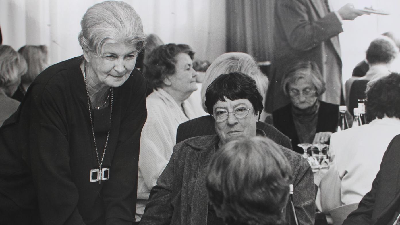 Heidi Rosenstock und Helga Trösken Heidi Rosenstock beugt sich über einen Tisch an dem Pröpstin Helga Trösken sitzt.