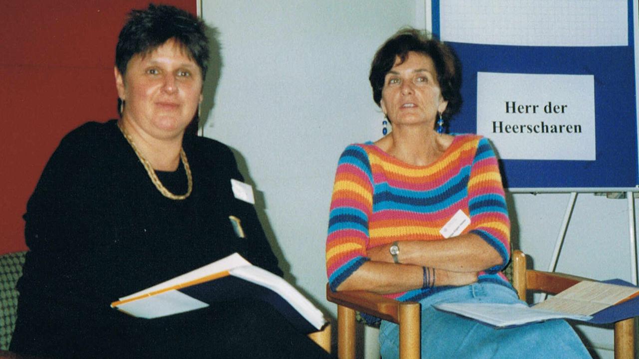 Hanne Köhler (l.) und Helga Engler-Heidle im Zentrum Bildung. Hanne Köhler (l.) und Helga Engler-Heidle sitzen nebeneinander mit Schreibblöcken auf dem Schoß. Im Hintergrund hängt ein Plakat auf dem steht: Herr der Heerscharen