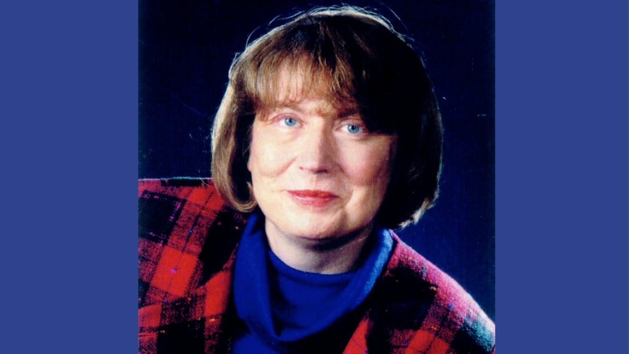 Leonore Siegele-Wenschkewitz Leonore Siegele-Wenschkewitz trägt einen blauen Rollkragenpullover und eine rot-schwarz karierte Jacke, sie hat halblange braune Haare und blickt nach links