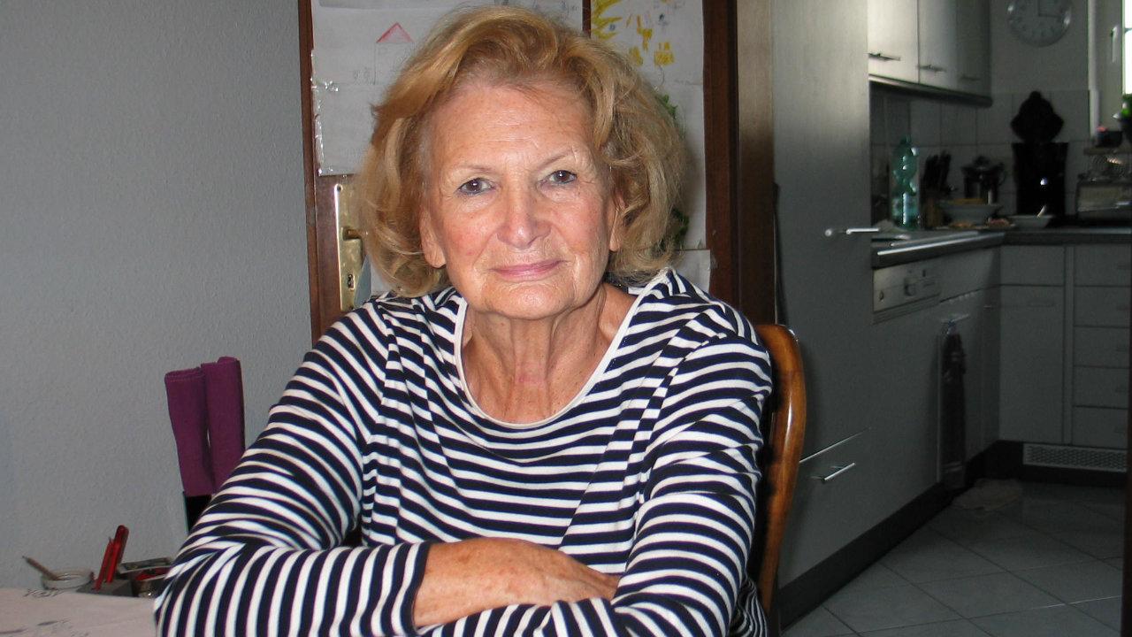 Brigitte Gößling Eine FRau mit halblangen gewellten dunkelblonden Haaren und einem gestreiften Pullover blickt in die Kamera, sie sitzt am Tisch