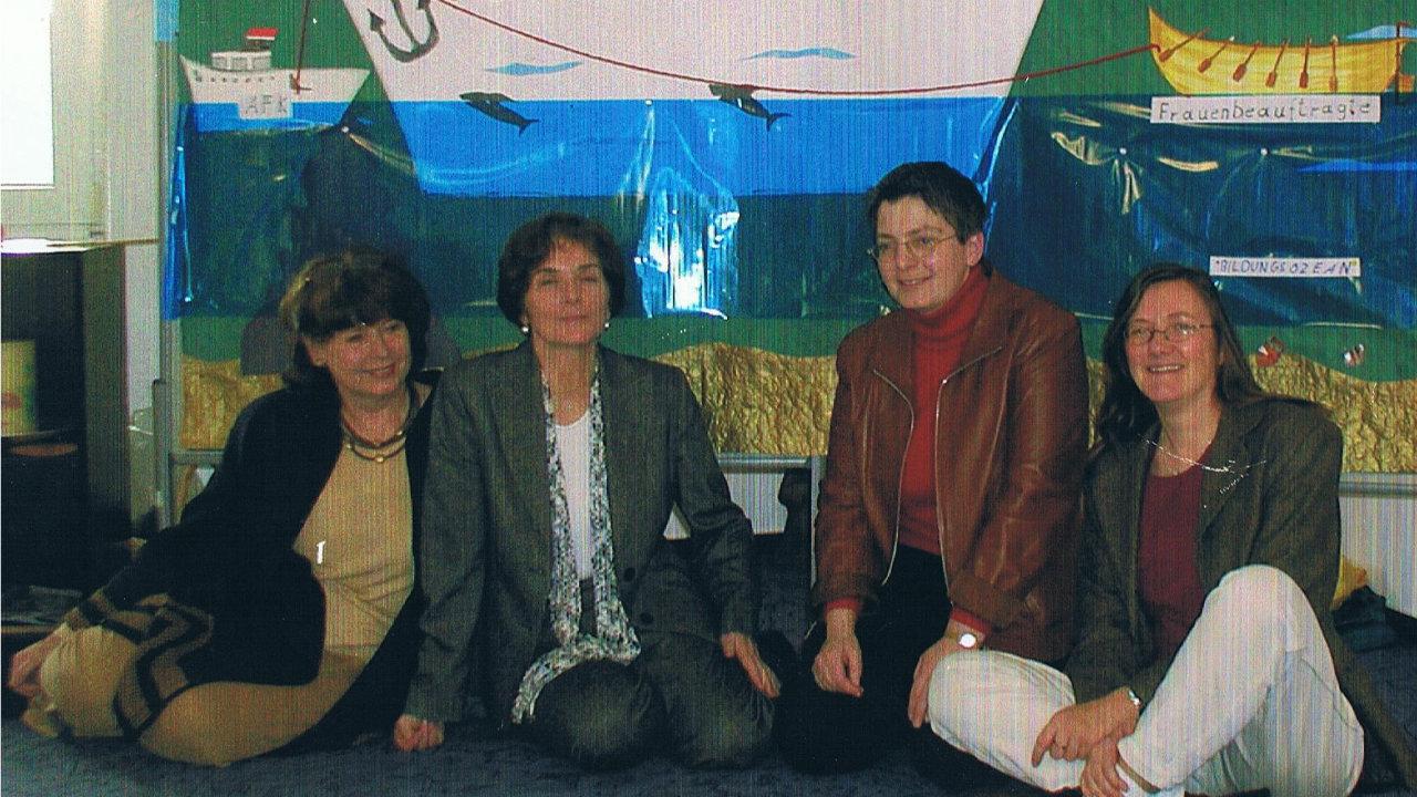 Das Leitungsteam der AG Frauen Die vier Frauen des Leitungsteams sitzen auf dem Boden, im Hintergrund ist ein gemaltes Schiff zu sehen.