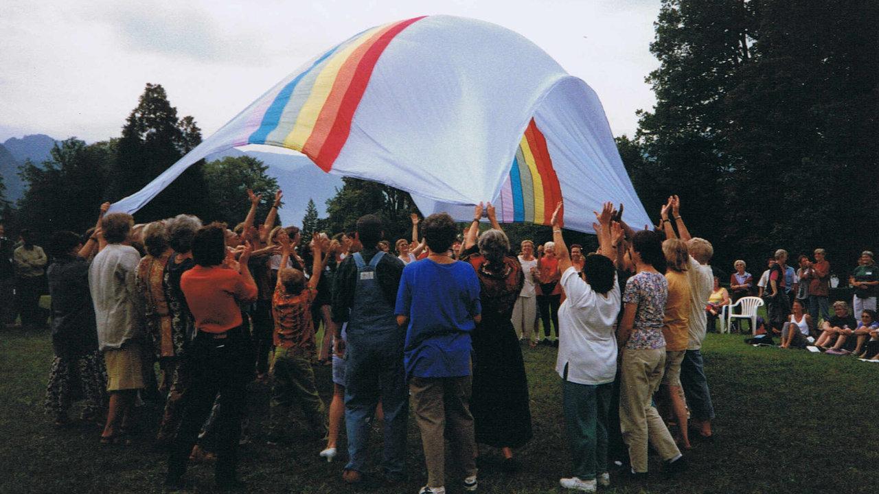 Eine Frauengruppe spielen mit einem Fallschirm in Regenbogenfarben.