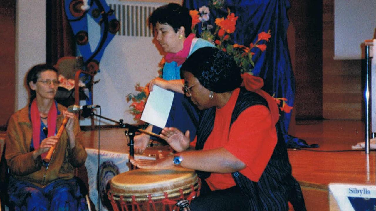 Europäische Frauensynode mit Musik Zwei Frauen spielen Trommeln, eine Frau klatscht im Hintergrund. Die drei Frauen machen Musik und sind fröhlich