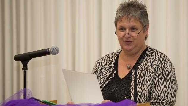 Hanne Köhler Hanne Köhler steht am Podest mit einem Mikrofon und hält ein Blatt Papier in den Händen