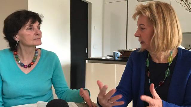 Helga Engler-Heidle und Ute Knie Helga Engler-Heidle mit grünem Pullover sitzt neben Ute Knie in schwarzem Oberteil und beide diskutieren miteinander und gestikulieren. Sie sitzen in einer Küche.: