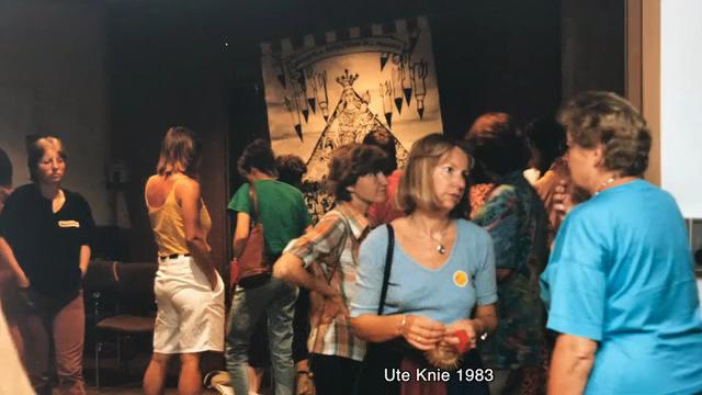 Werkstatt Feministische Theologie 1983 zwei Frauen unterhalten sich im Vordergrund des Bildes, im Hintergrund sind weitere Frauen zu sehen, die in Gespräcehen vertieft sind.