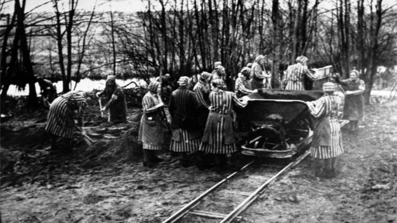 Konzentrationslager Ravensbrück Zwangsarbeiterinnen mit gestreifter Einheitskleidung schaufeln Erde in einem Wagen der auf Gleisen fährt