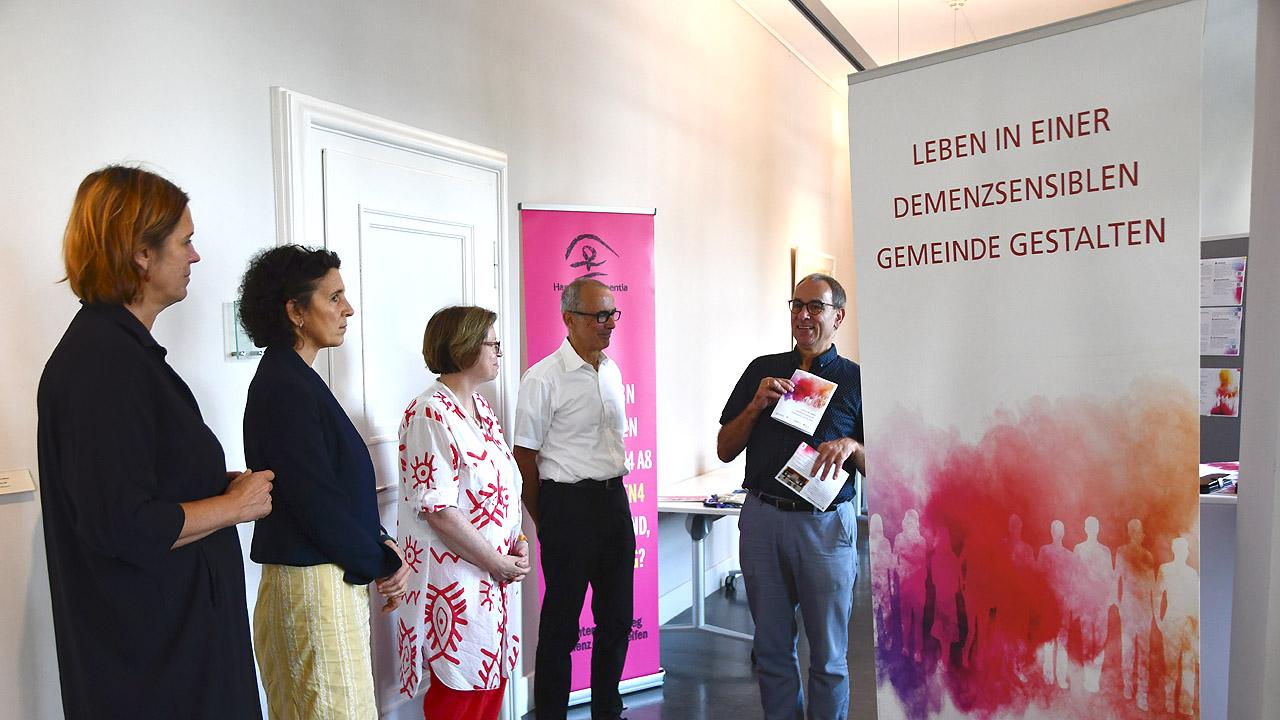 Schulung zum Thema Demenz Vier Menschen hören einem Vortragenden zu