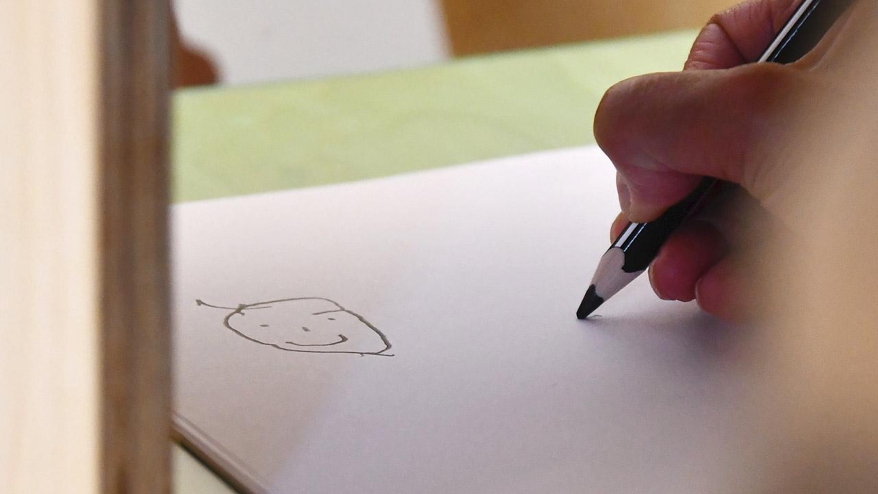 Demenzsimulator Ein gemalter Umriss eines Gesichtes mit schrägem Mund