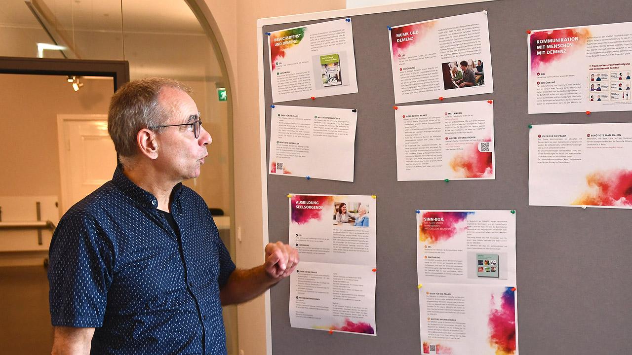 Schulung zum Thema Demenz Ein Mann steht vor einem Pinnboard und spricht