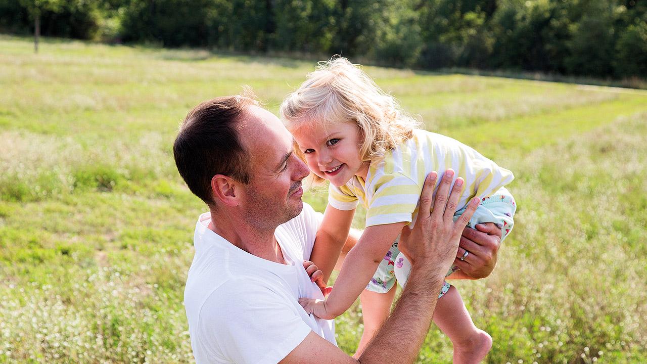 Vater-Kind-Kur Ein Vater hebt seine blonde Tochter hoch