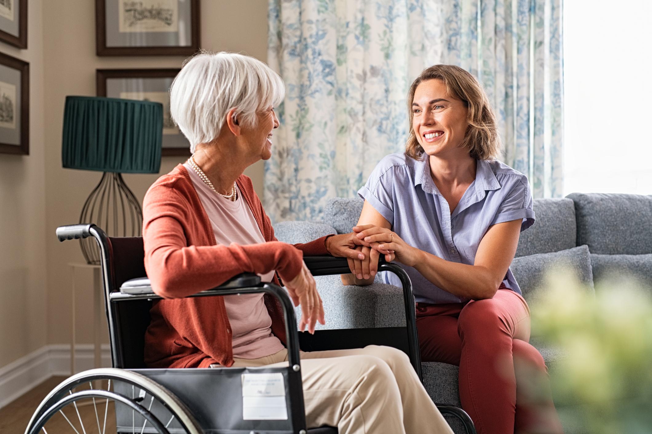 alte Dame im Rollstuhl im Gespräch mit einer jüngeren Frau 