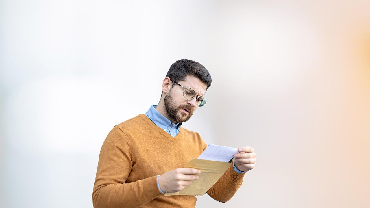 Ein Mann blickt sorgenvoll auf einen offiziellen Brief