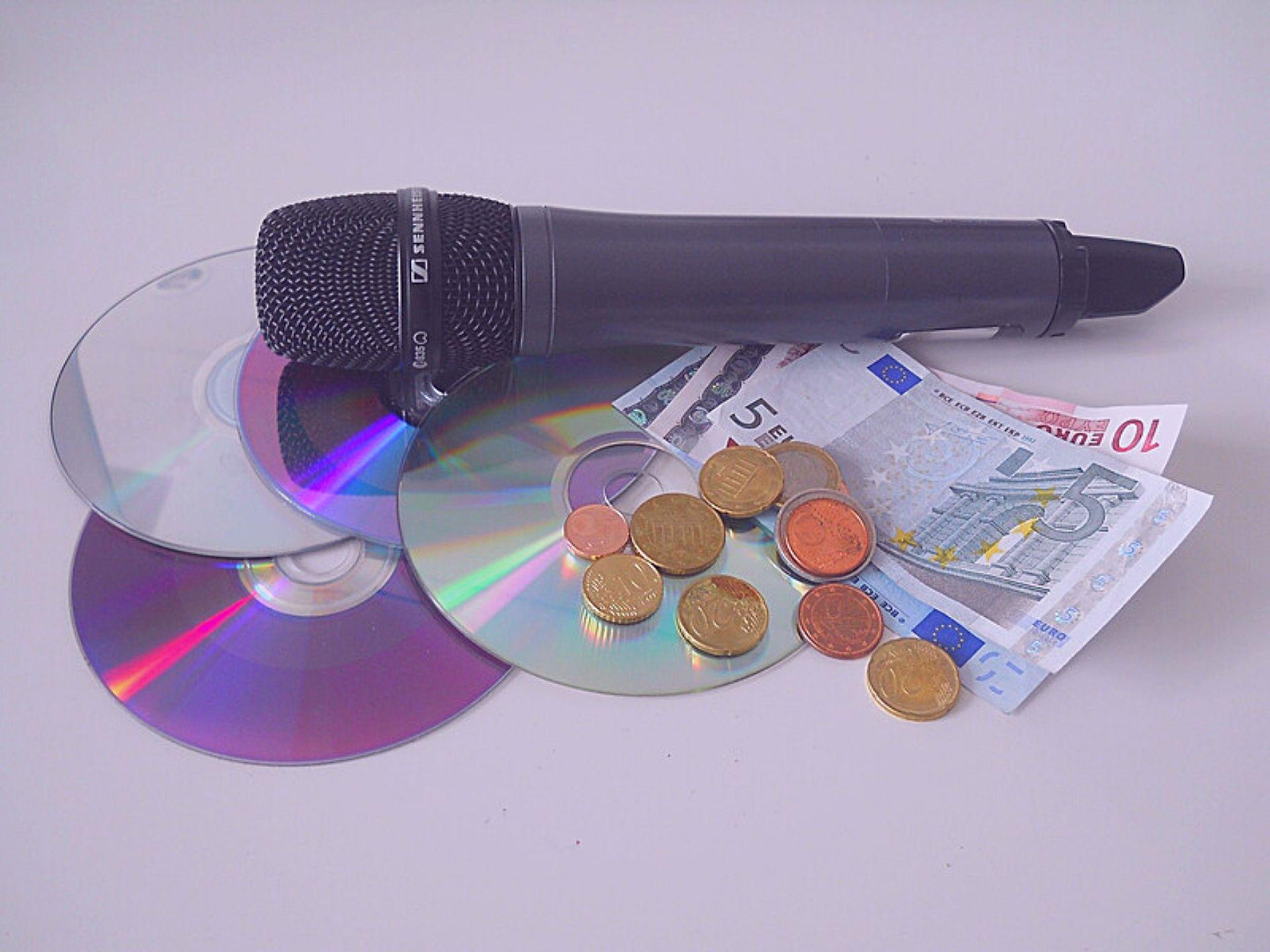 3 CDs, 1 Mikro und Bargeld liegen auf einem Tisch