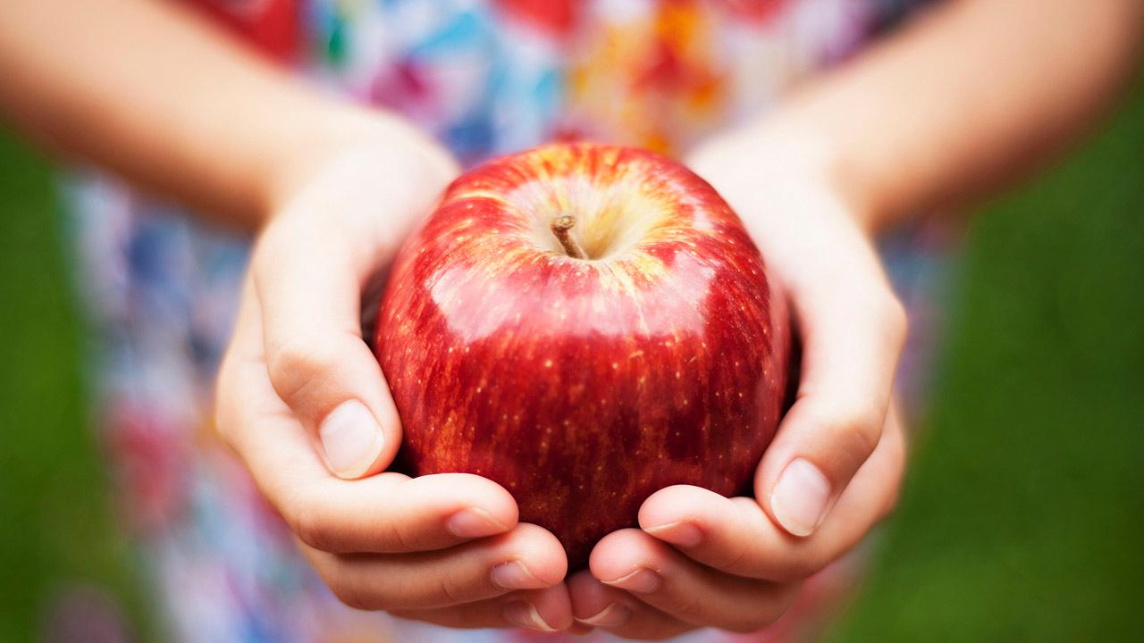 Hände, die einen roten Apfel halten