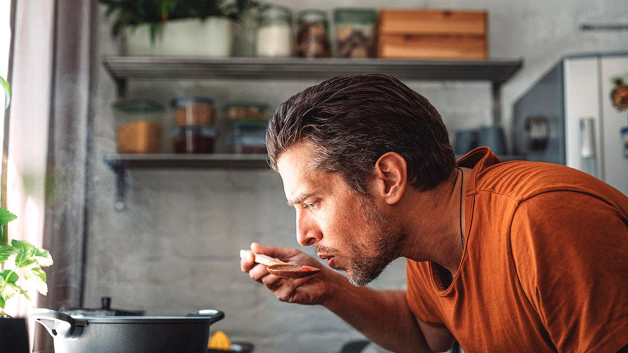 Mann schmeckt ab beim Kochen