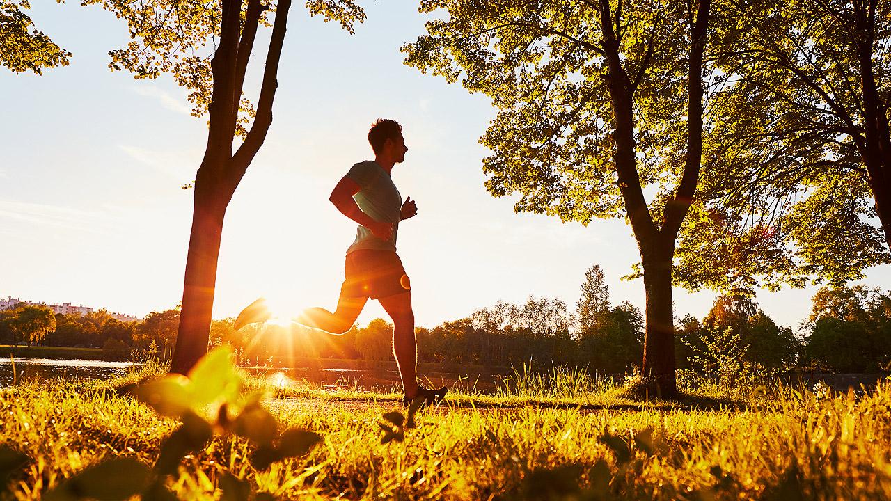 Spirituelles Laufen Ein Mann joggt durch die Natur bei Gegenlicht