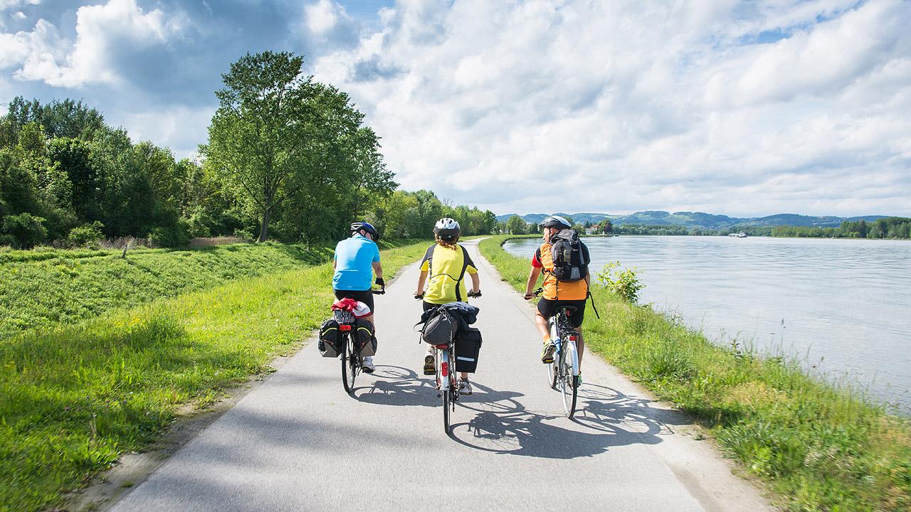 Drei Menschen, die Fahrrad an einem Fluss fahren