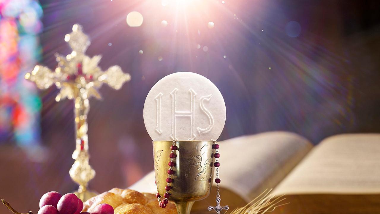 Eucharistie Kelch mit Oblate, daneben ein Kreuz