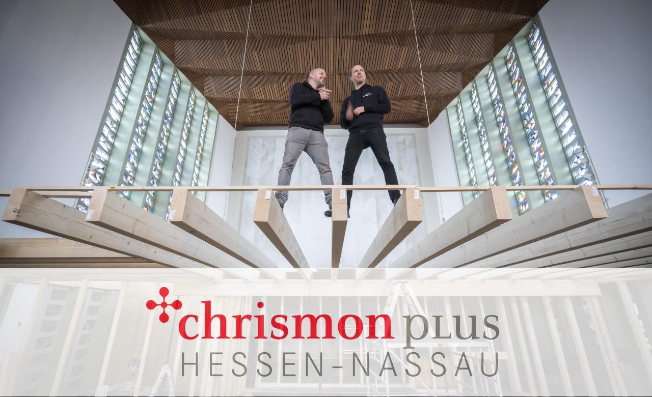 Zwei Handwerker stehen auf auf Balken im Inneren der Kirche.
