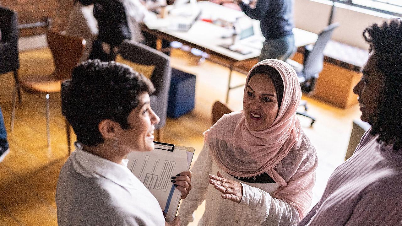 Eine Frau mit Kopftuch spricht mit anderen Frauen, die kein Kopftuch tragen