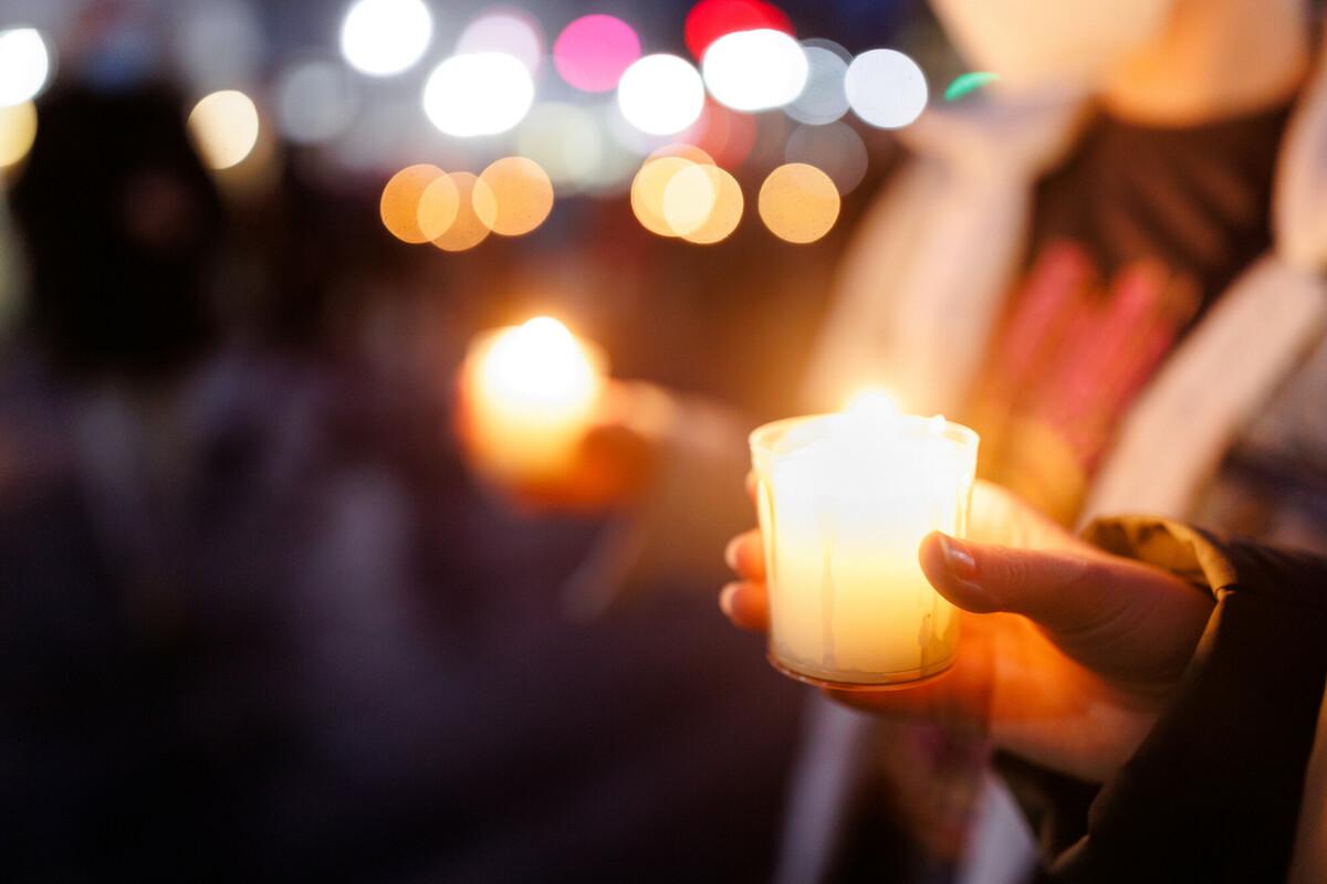 Mehrere Menschen stehen im Gebet zusammen und halten brennende Kerzen in den Händen